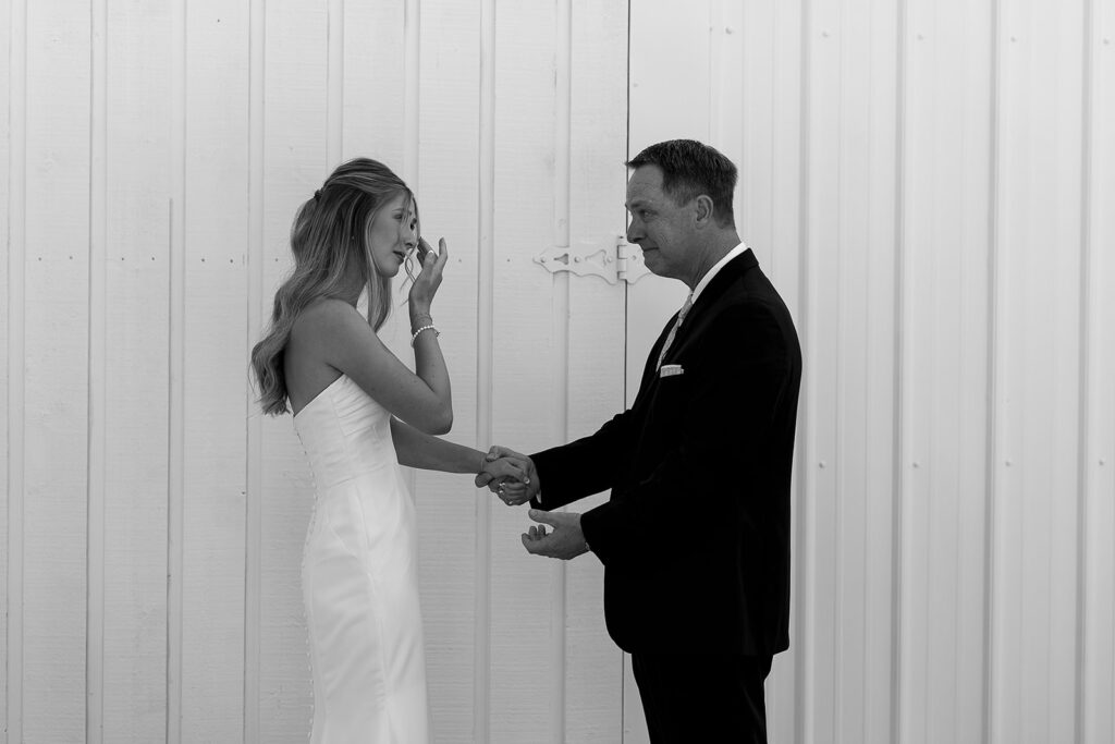 bride wiping away a tear when her dad sees her for the first time in her dress