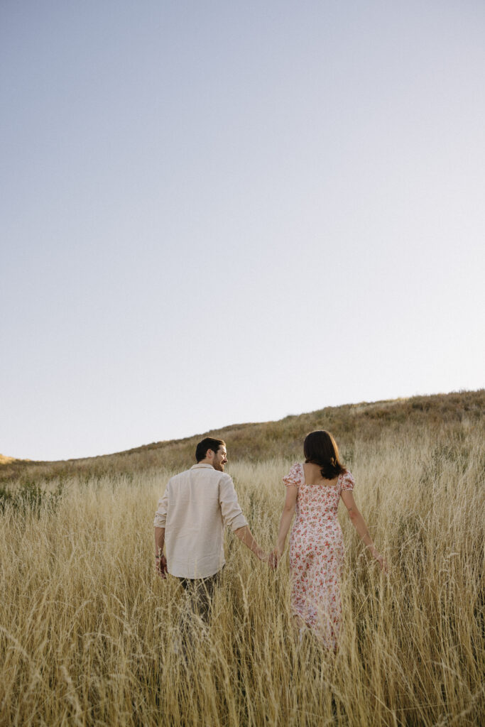 couple walking in open field in fort collins during their colorado engagement