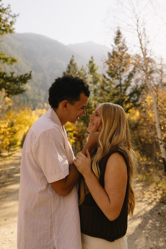 couple holding onto each other in aspen surrounded by trees