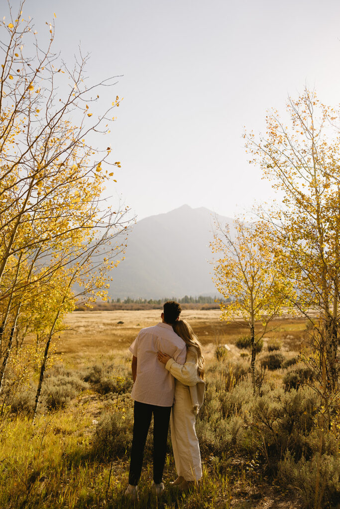 couple holding onto each other in aspen surrounded by trees