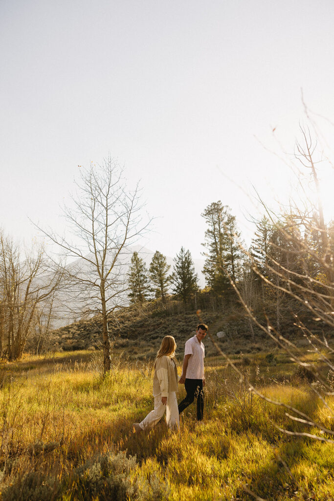 couple walking holding hands in aspen surrounded by trees