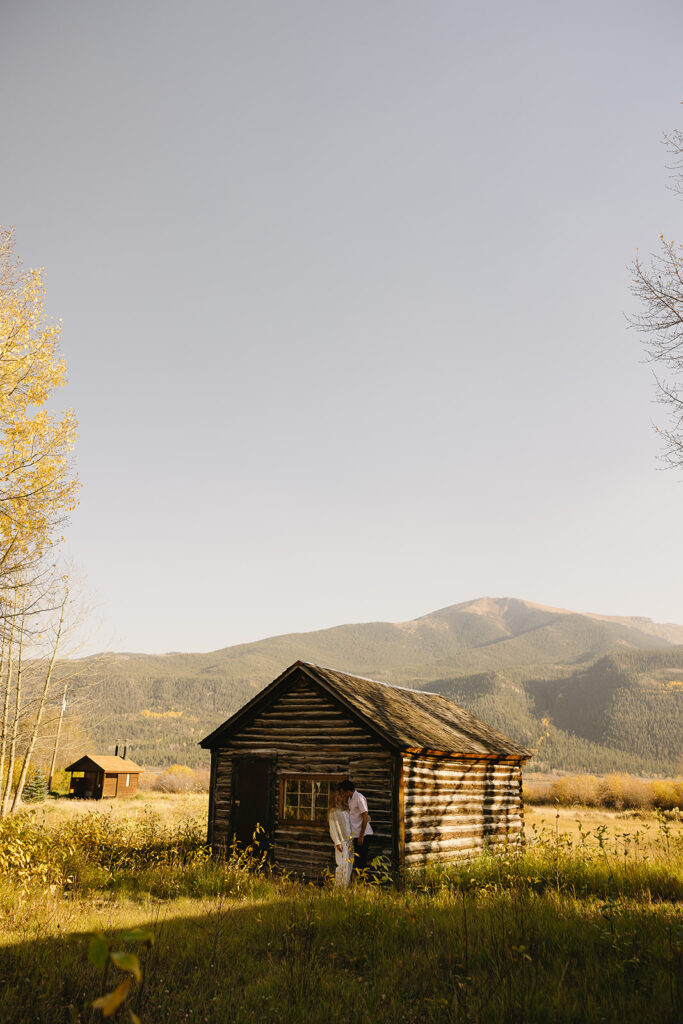 couple standing in front of barn in aspen surrounded by trees