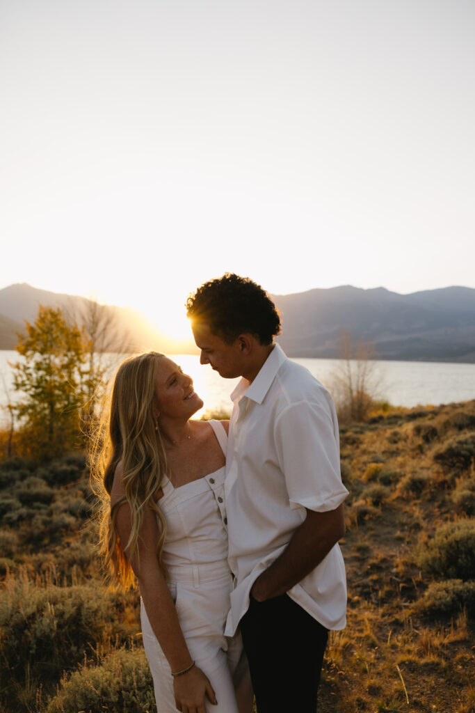 couple standing in front of lake in aspen surrounded by trees