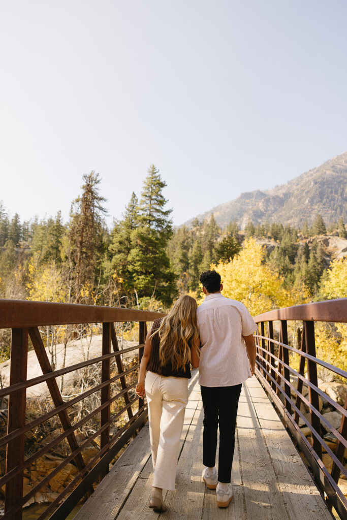 couple walking with each other on bridge during their colorado engagement photos at aspen