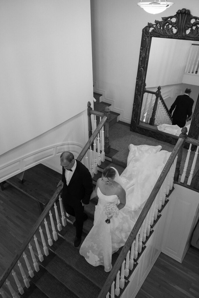 bride being walked down stairs by her dad on her way to ceremony