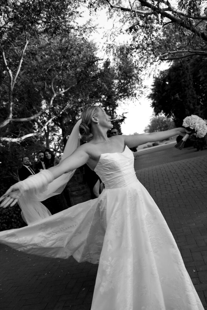 bride dancing in her wedding dress holding her luxe wedding flowers 