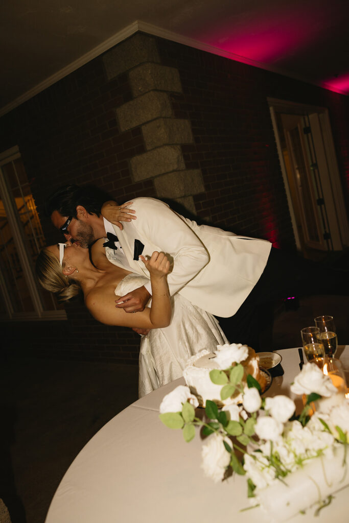 bride and groom kissing after cutting their wedding cake