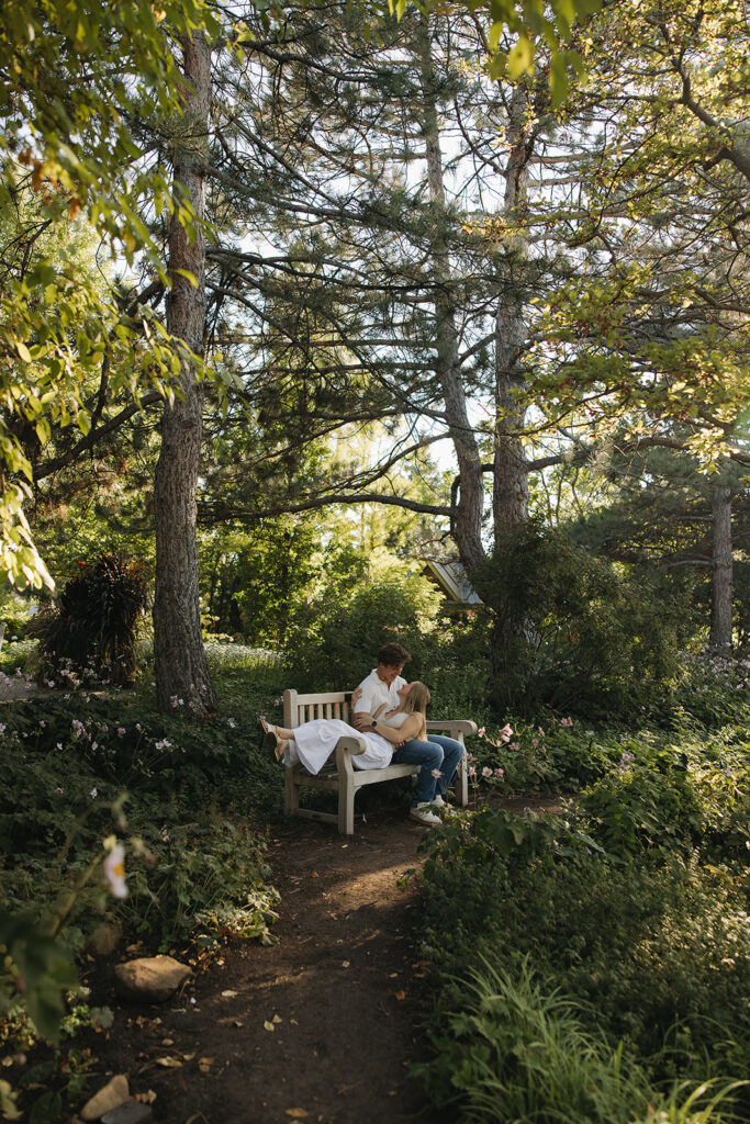 couple sitting on bench at denver botanical gardens during their colorado engagement