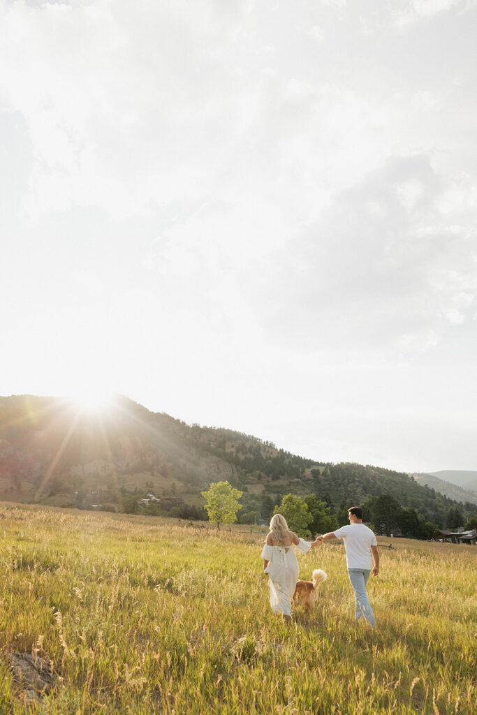 couple walking in open field with dog at boulder 