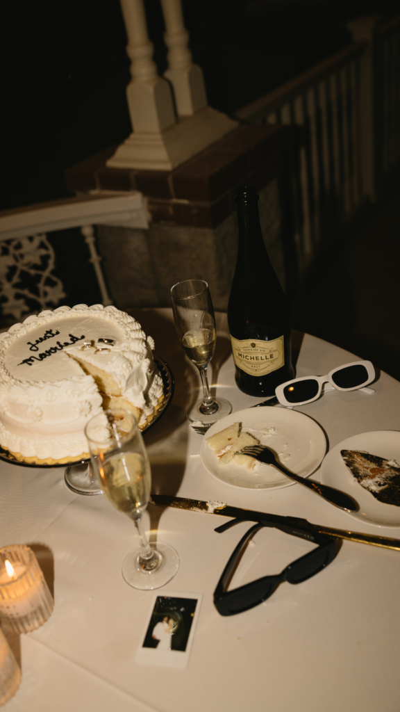 wedding flatlay with wedding cake, champagne, fun sunglasses and polaroid pictures