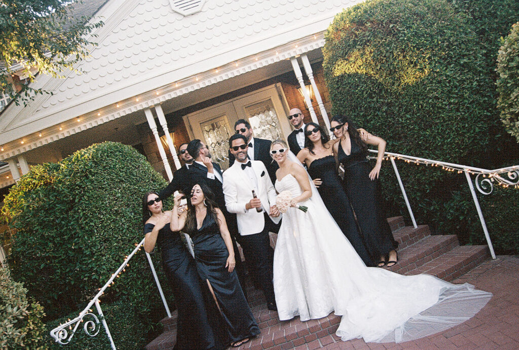 bride and groom standing with their wedding party in front of their venue captured through film photography