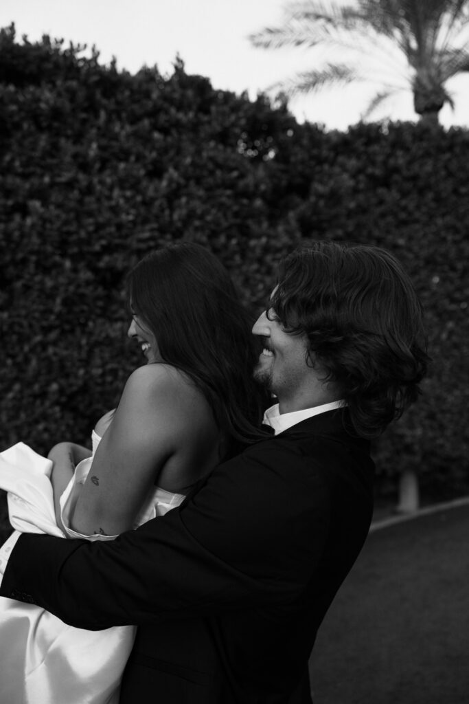 grooms hugging bride and swinging her around