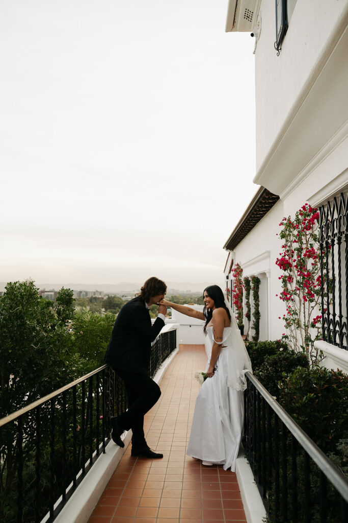 groom kissing brides hand outside of their wedding venue on their wedding day