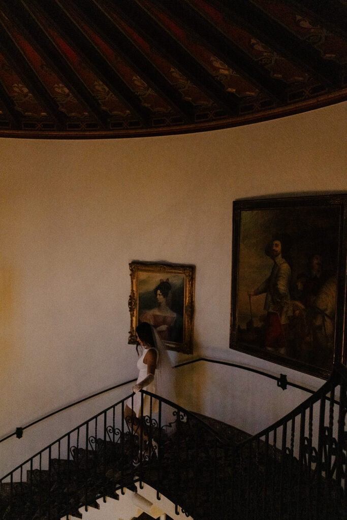 bride walking down the staircase surrounded by paintings