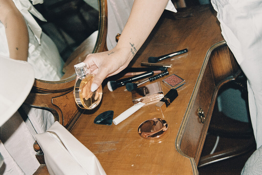 detail photos of bride holding perfume with wedding makeup on desk 