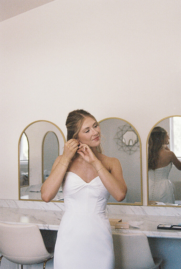 bride putting in her earrings on her wedding day