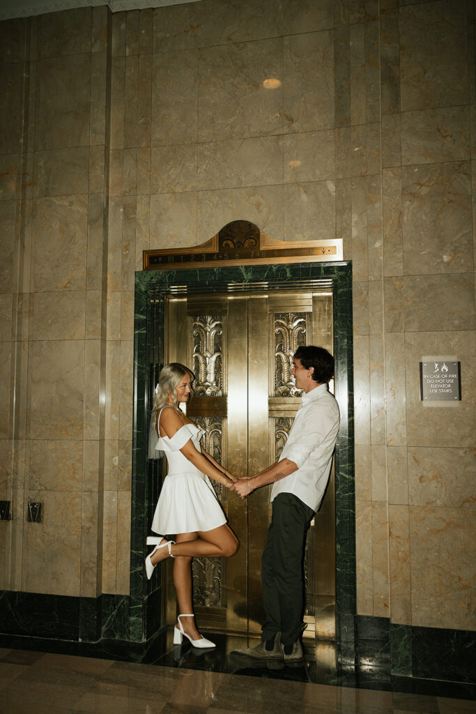 couple standing in front of elevator holding hands during couples session