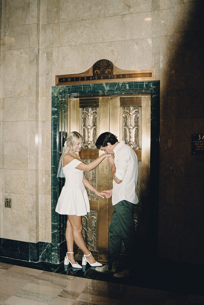 film photo of couple standing in front of elevator during engagement session