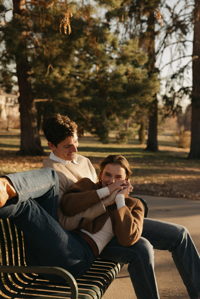 couple sitting on park bench with each other at cheesman park in denver