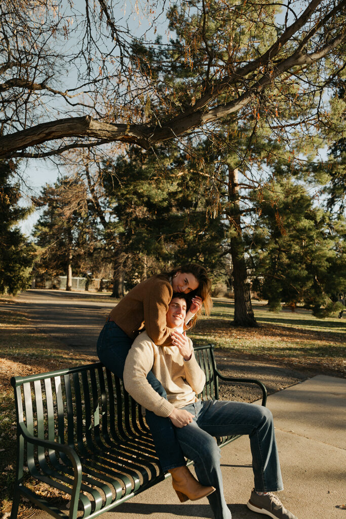 couple sitting on park bench with each other at cheesman park in denver