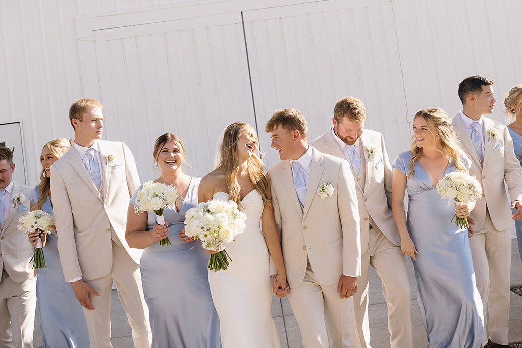 bride and groom walking to reception surrounded by bridesmaids and groomsmen