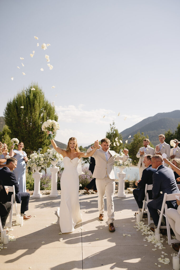 bride and groom walking down the aisle after their vows with rose pedals falling around them