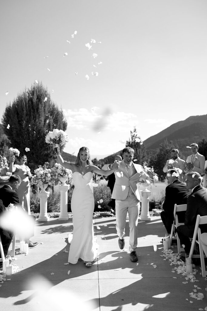 black and white photo of bride and groom walking down the aisle after getting married