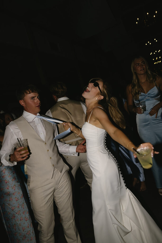 bride pulling grooms tie to come dance with her