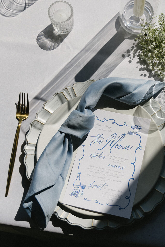 detail photo of the wedding day menu with blue napkins and baby's breath flowers