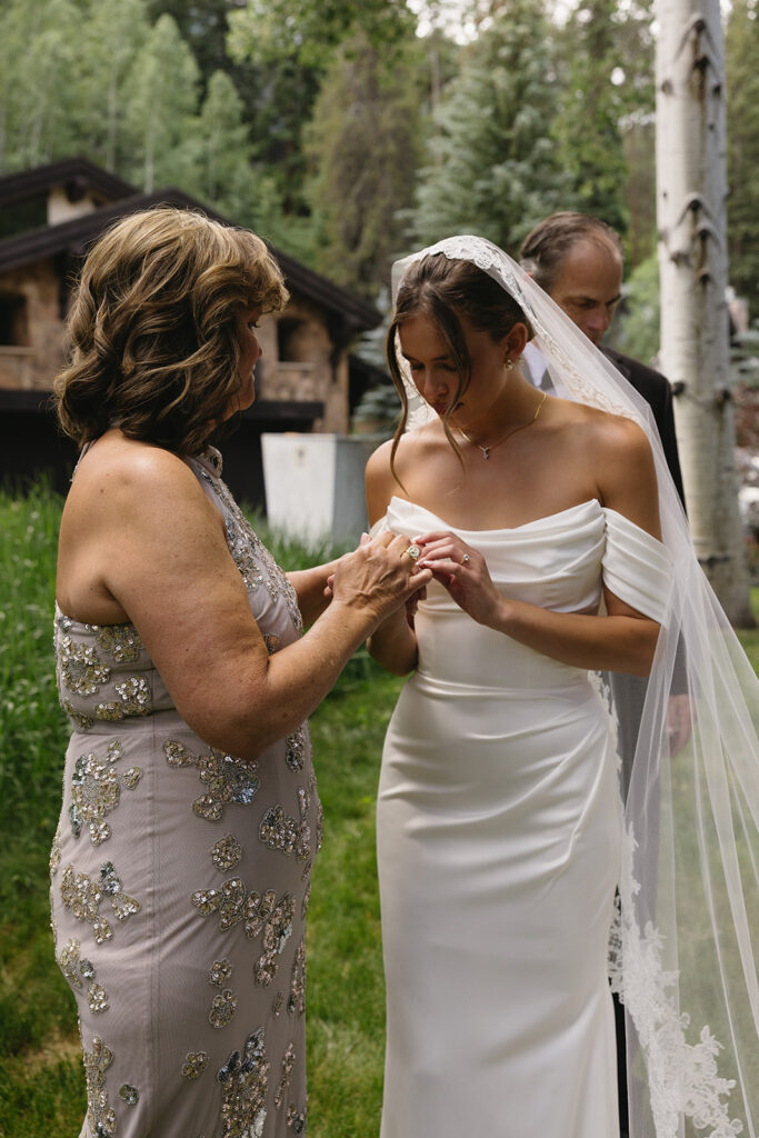 mother of the bride helping bride get ready for wedding ceremony