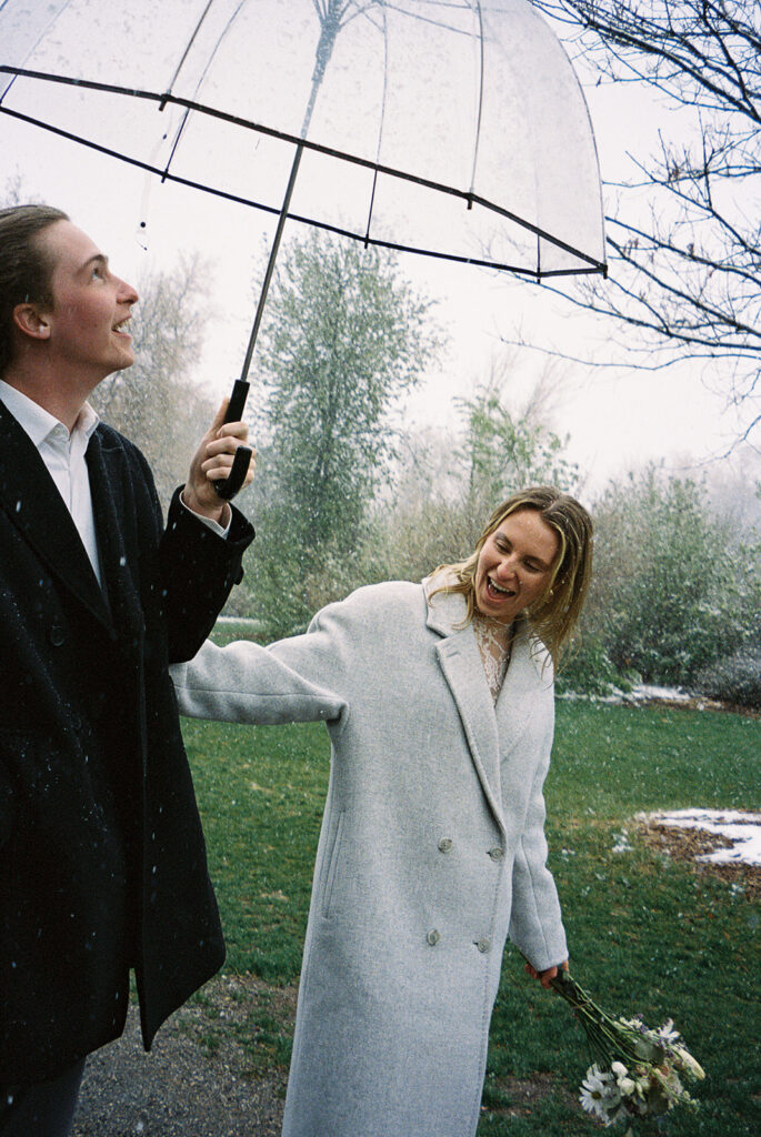 bride and groom walking in the rain with umbrella