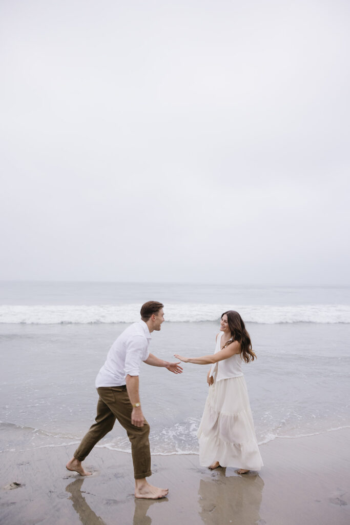 candid photos of a couple running on the beach barefoot