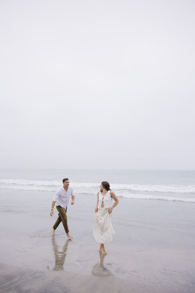 candid photos of a couple running on the beach barefoot
