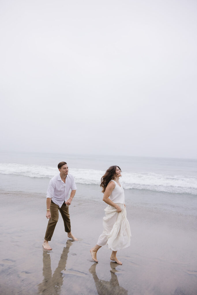 candid photos of a couple running on the beach barefoot