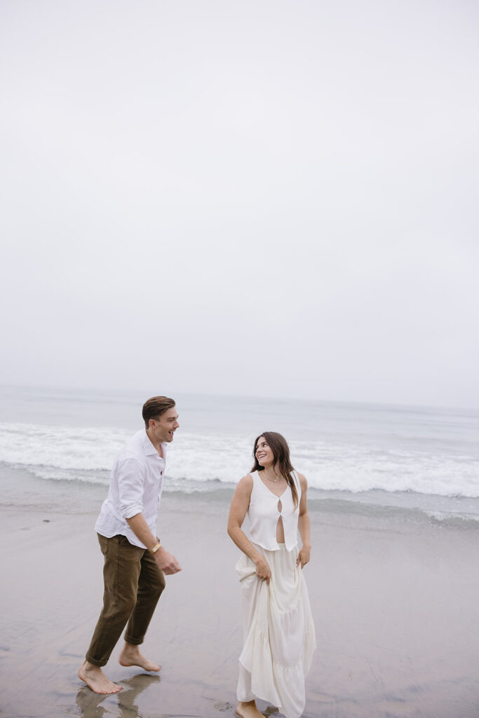 candid photos of a couple running on the beach barefoot