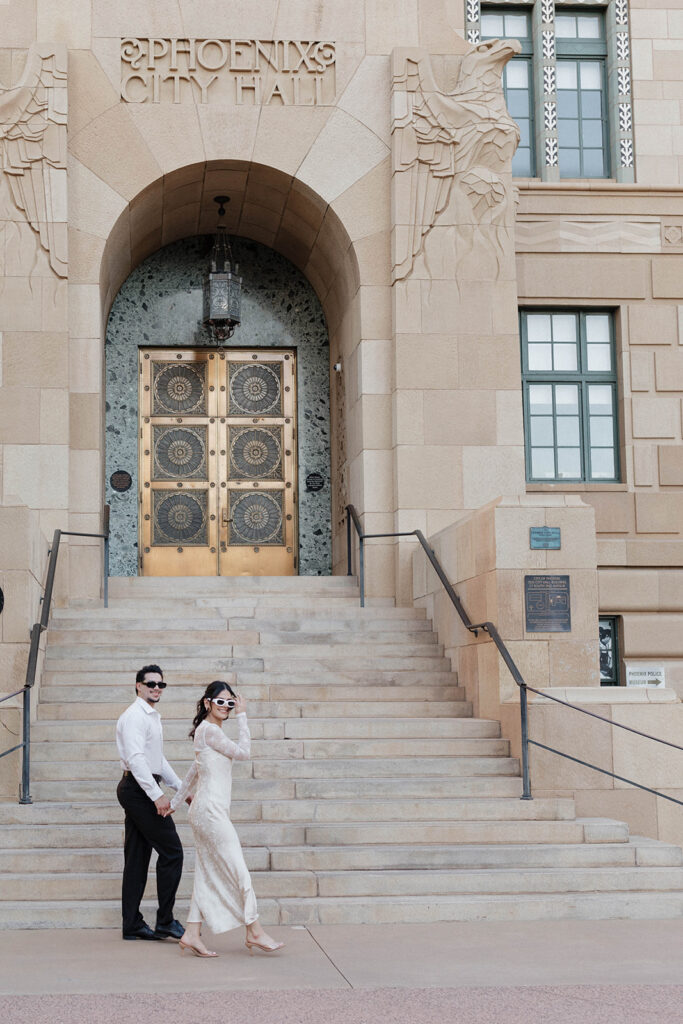 couple holding hands and walking in front of phoenix city hall