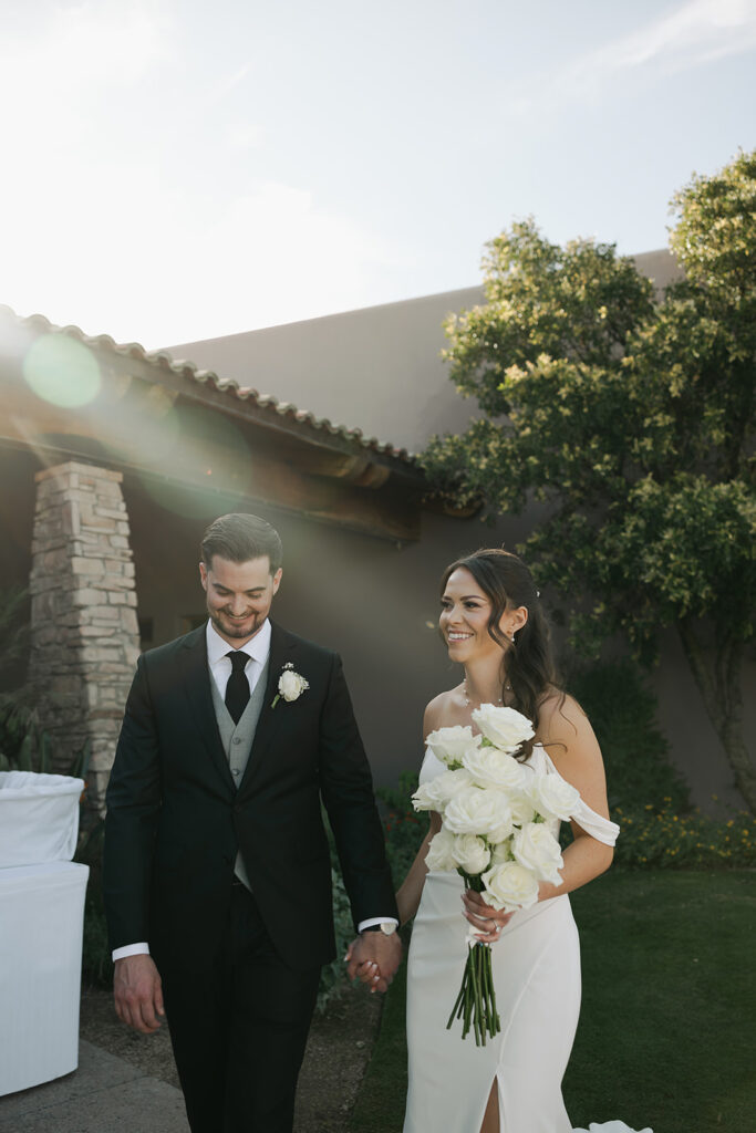 bride and groom smiling while holding hands during golden hour