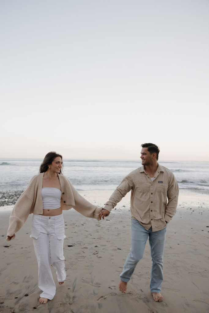 couple holding hands and running on the beach at sunrise