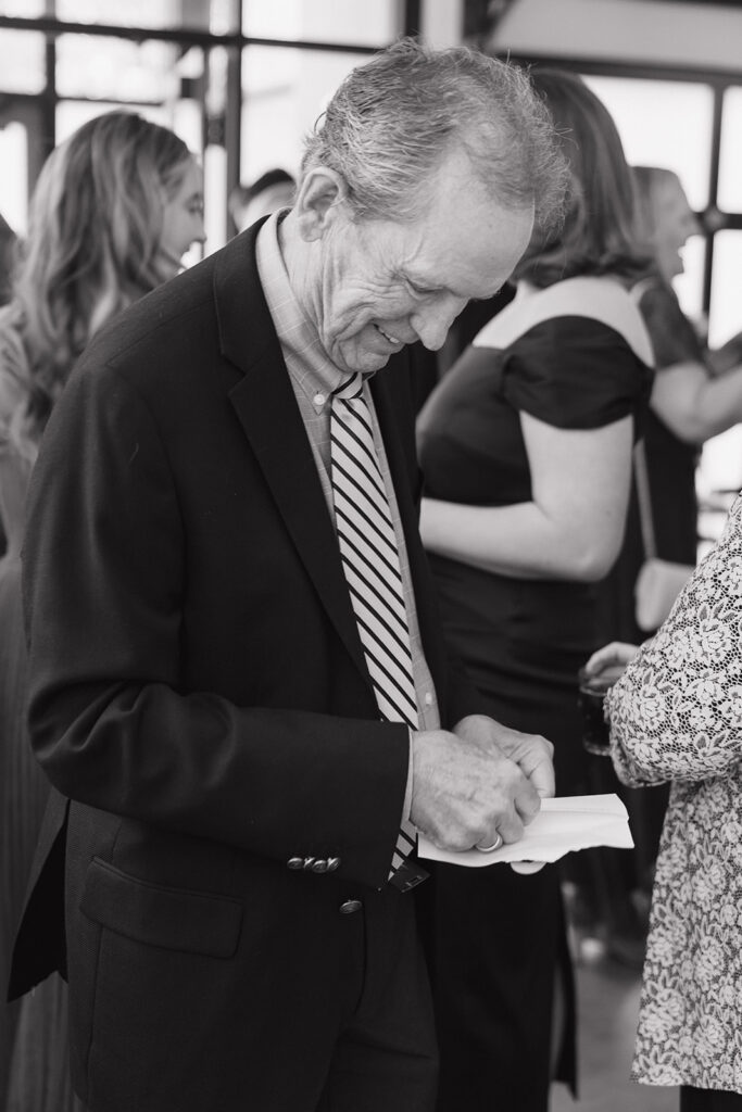 black and white documentary style wedding photography of guests. opening letters from the bride and groom
