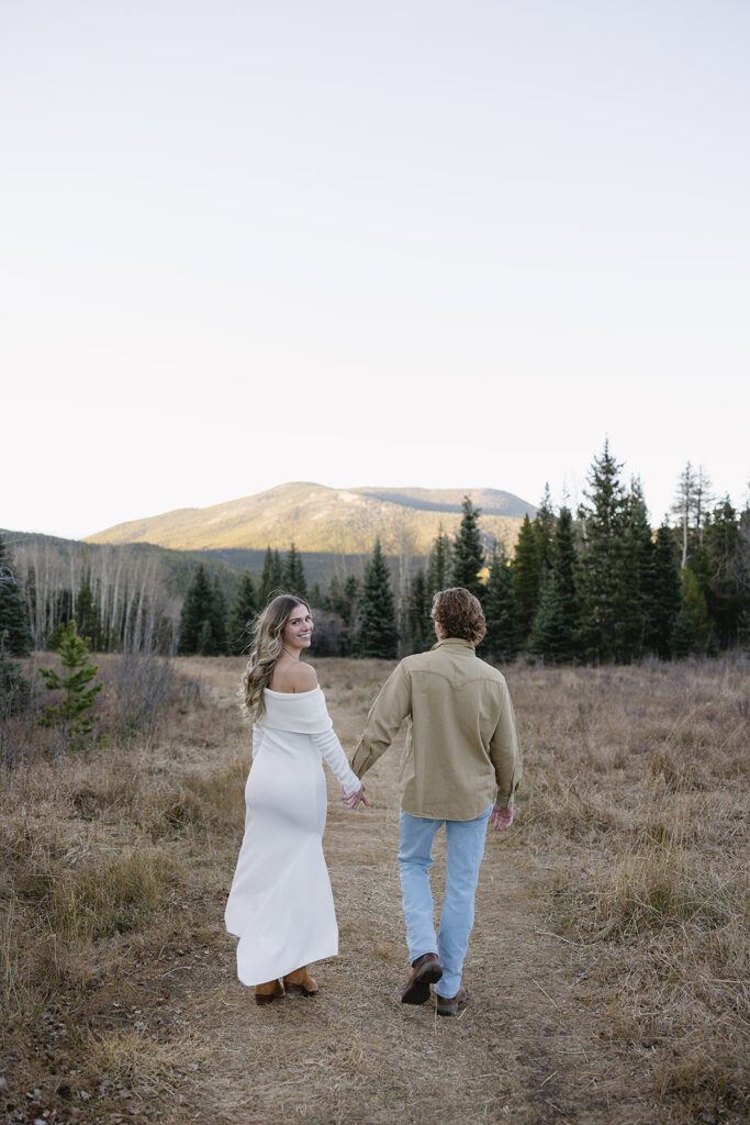 couple holding hands and walking toward the colorado mountains in evergreen colorado