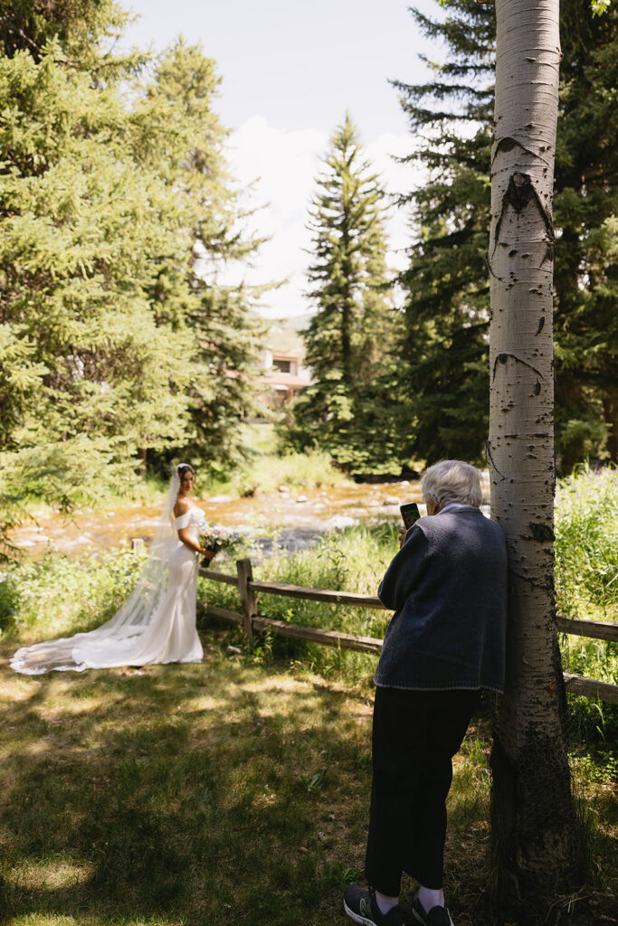 documentary style wedding photography of grandma taking photo of bride