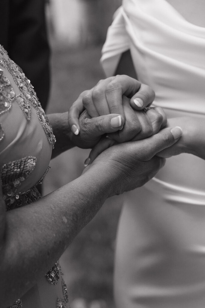 mother of the bride and bride holding hands for a documentary style wedding photo